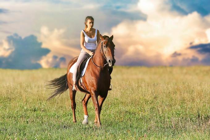 A woman riding a horse confidently. 